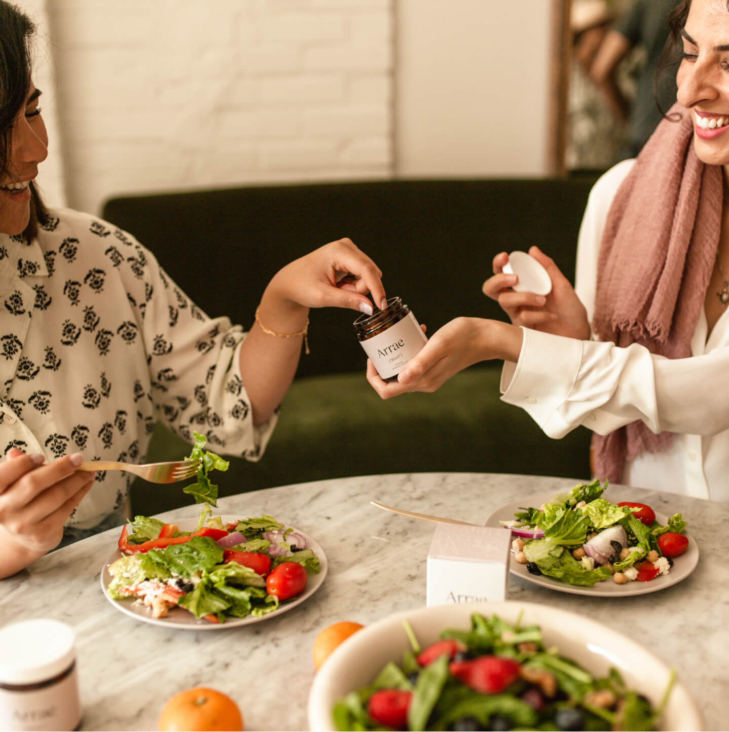 2 women enjoying food, and one is offering the other Arrae Bloat