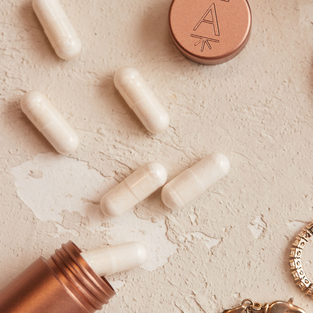Arrae Carry-On Capsule Case in Rosy Peach with capsules laying next to it