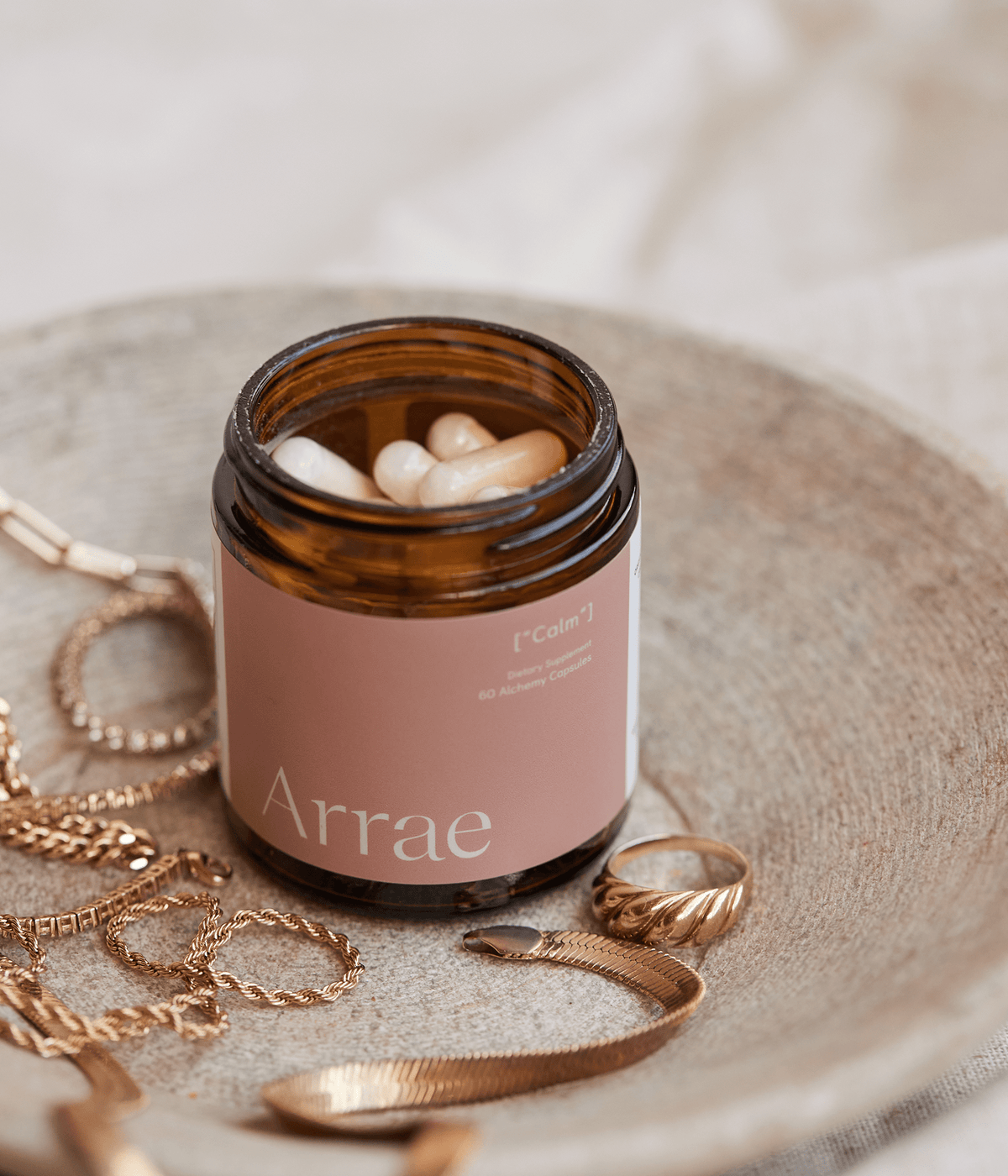 Arrae Calm Supplement surrounded by jewellery - A bottle of 60 capsules featuring a blend of natural ingredients, formulated to promote relaxation and reduce stress and anxiety